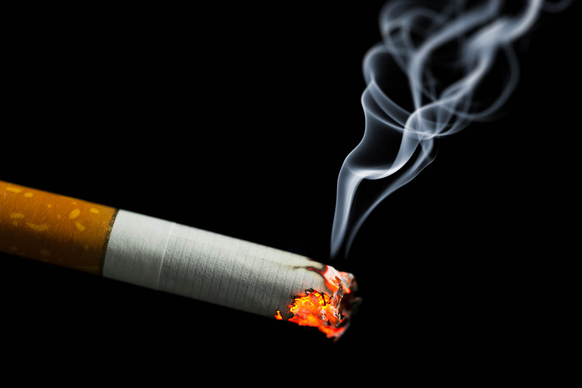 burning cigarette with smoke on black background